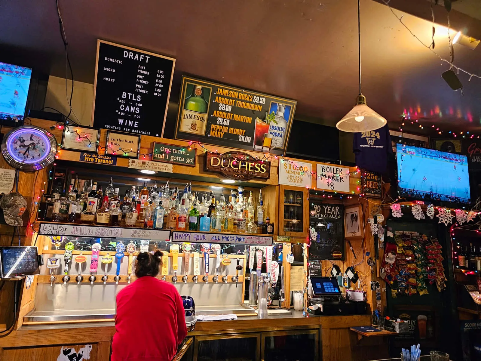The bar at the Duchess Tavern: draft board, bottles, string lights and hand-lettered signs