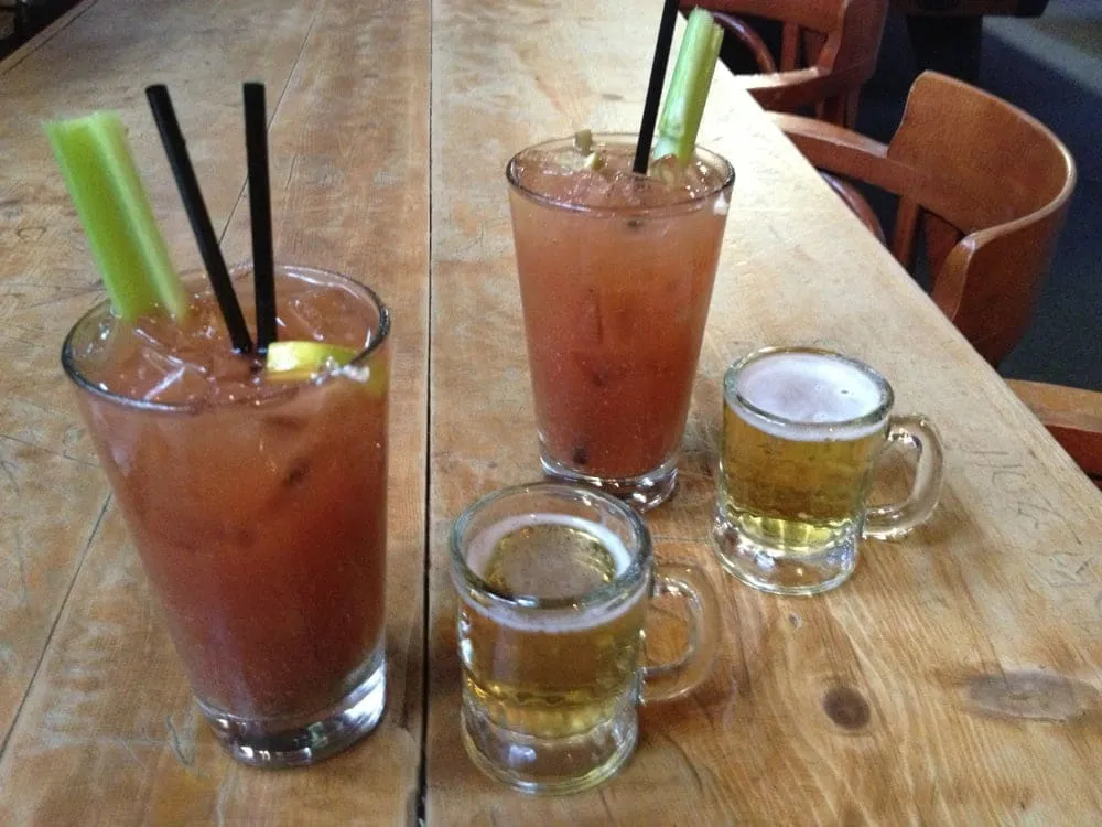 Two bloody marys with celery and beer sidecars on the wooden bar