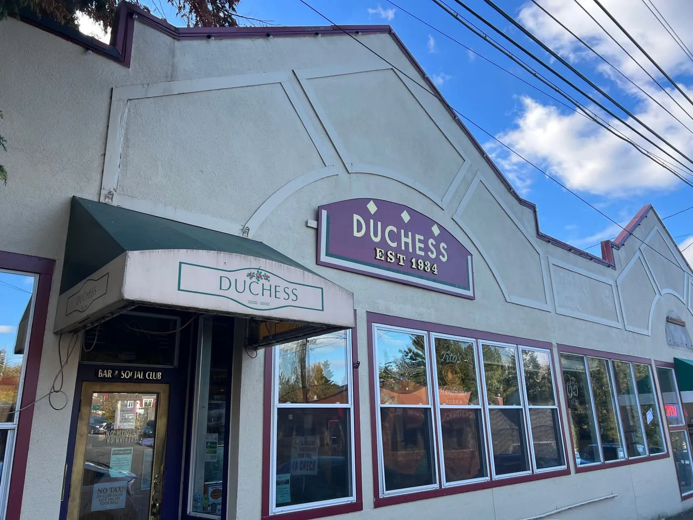 The Duchess Tavern storefront by day on NE 55th Street, with its green awning and the Duchess Est 1934 sign