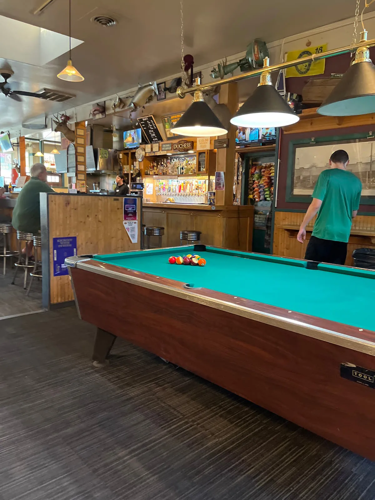 A pool table racked and lit by brass shade lamps in the back room of the Duchess Tavern