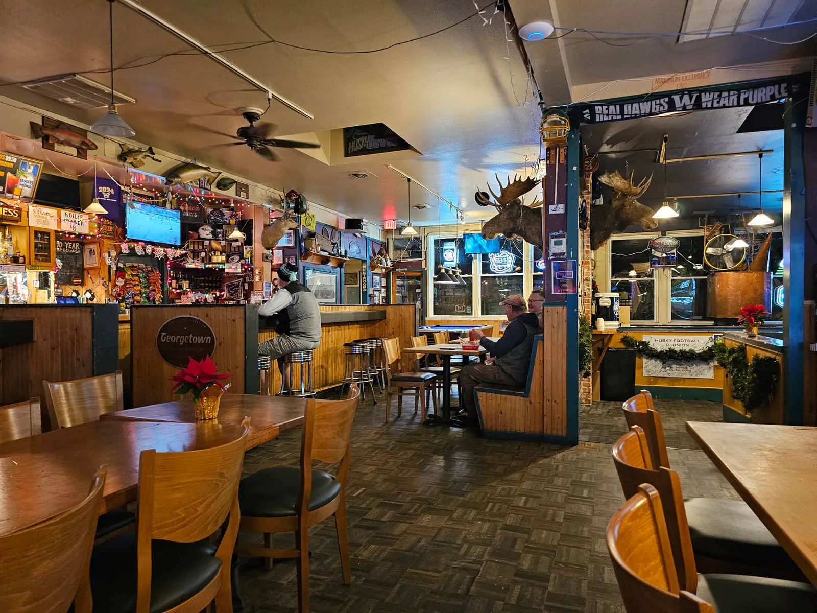 Inside the Duchess Tavern: wooden booths and tables, mounted moose heads and a Real Dawgs Wear Purple banner over the bar