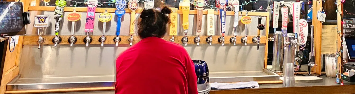 The row of draft handles along the bar at the Duchess Tavern, a bartender pouring underneath them